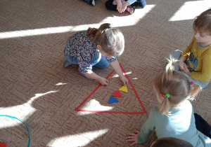 Dziewczynka układa figurę geometryczną na dywanie