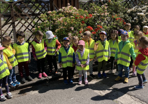Grupa dzieci przedszkolnych stoi przy drewnianym ogrodzeniu