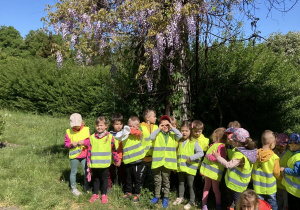 Grupa dzieci przedszkolnym stoi razem pod drzewem.