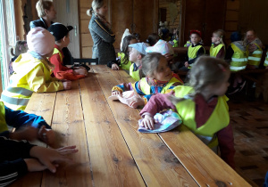 Dzieci siedzą przy drewnianym stole.