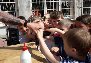 Grupa dzieci próbuje wkręcić śrubkę