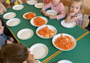 Dzieci siedzą przy stole i smakują marchweki