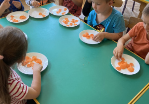 Dzieci siedzą przy stole i smakują marchweki