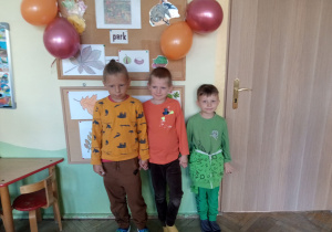 Troje dzieci stoi przy ścianie