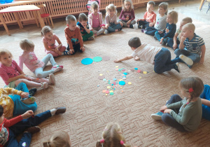 Dzieci siedzą wspólnie w kole na dywanie