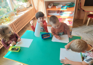 Dzieci siedzą przy stoliku i wykonują zadania