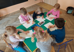 Dzieci siedzą przy stoliku i wykonują zadania