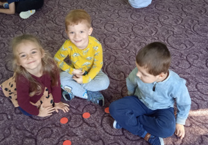 Troje dzieci siedzi na dywanie
