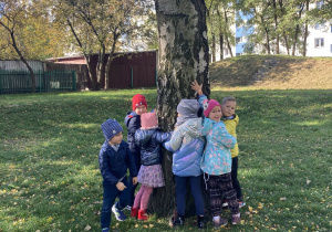 Dzieci stoją przy drzewie