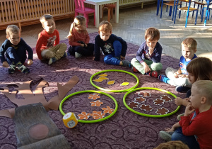 Dzieci wspólnie siedzą na dywanie i wykonują zadanie