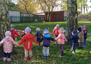Dzieci wspólnie stoją w gromadzie przy drzewie