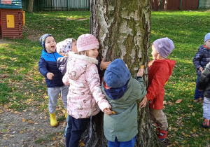 Dzieci wspólnie stoją w gromadzie przy drzewie