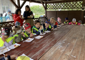 Dzieci siedzą przy posiłku na terenie stadniny