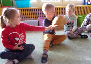 Dzieci siedzą na dywanie i ogladają dynie