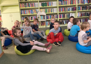 Dzieci siedzą na dywanie w bibiliotece
