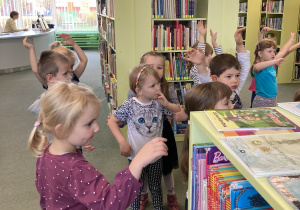 Dzieci stoją przy regale z książkami