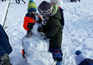 dzieci lepią bałwana ze śniegu