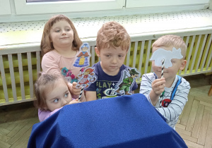 Dzieci stoją przed pudełkiem przykrytym materiałem