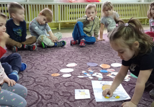 Dzieci wspólnie układają elementy na dywanie