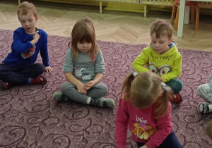 Dzieci wspólnie układają elementy na dywanie