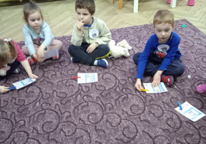 Dzieci wspólnie siedzą na dywanie
