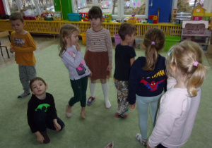 Dzieci stoją w rozsypce na dywanie