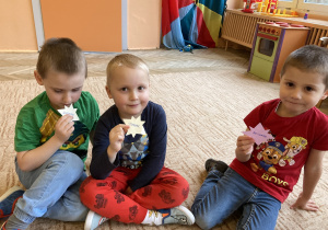 Dzieci siedzą na dywanie trzymają gwiazdki