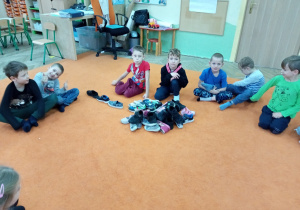 Dzieci siedzą na dywanie i ukldaja buty