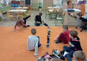 Dzieci siedzą na dywanie i ukldaja buty