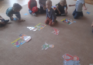 Dzieci siedzą na dywanie w otoczeniu elementów układanki