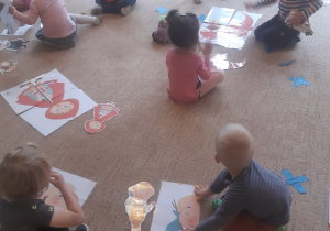 Dzieci siedzą na dywanie w otoczeniu elementów układanki
