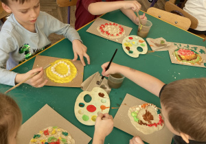 Dzieci wspólnie siedzą przy stoliku i wykonują zadanie- pizzę z masy solnej