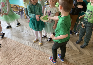 Chłopiec przekazuje dziewczynce plastikowy talerzyk z rysunkiem żabki