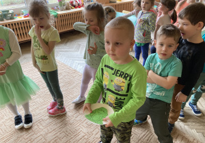 Chłopiec stoi w rzędzie trzymając w ręku plastikowy talarzyk