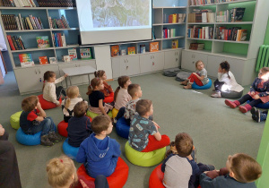 Dzieci siedzą w sali bibliotecznej i oglądają film