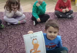 Chłopiec trzyma ilustrację kota w ręce