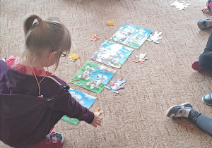Dziewczynka uklada obrazki na dywanie