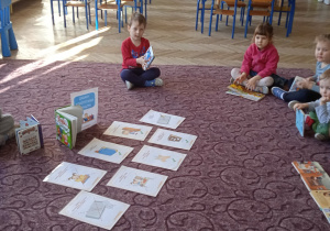 Dzieci siedzą na dywanie pośród książek