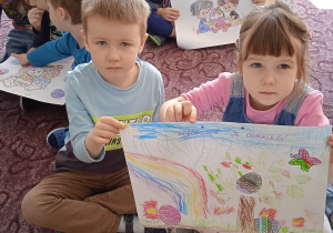 Dwoje dzieci prezentuje wykonaną przez siebie pracę