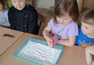 Dziewczynka wlewa barwnik do mąki.