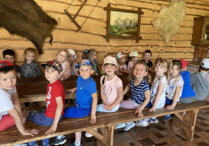 Dzieci siedzą przy drewnianiej ławie