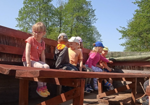 Dzieci siedzą wokół drewnianego stolika.