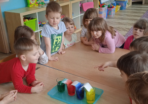 Dzieci obserwują, jak zabarwia się papier na różne kolory.