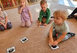 grupa dzieci na dywanie z obrazkowymi puzzlami