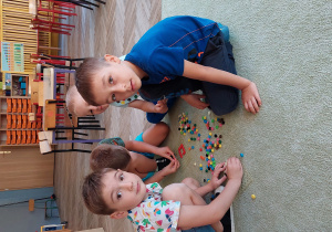 grupka chłopców siedząca na dywanie z małymi pomponikami