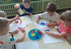 grupa dzieci maluje skrawki folii bąbelkowej farbami