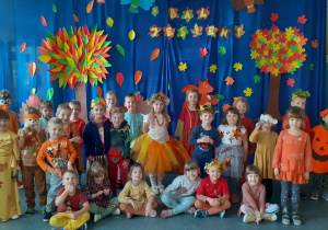 grupa dzieci w strojach jesiennych na tle jesiennej dekoracji