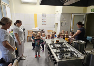 grupa dzieci z paniami kucharkami w kuchni przedszkolnej