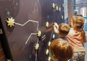 dzieci dotykające podświetlane gwiazdy na ścianie gwiazdozbioru