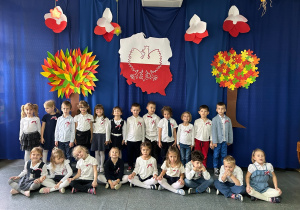 grupa dzieci pozuje na tle dekoracji patriotycznej